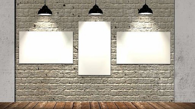 three canvas on brick wall lit by artistic gallery lights